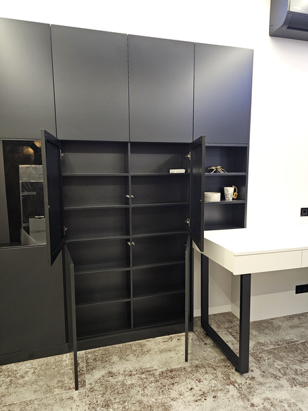 Корпусный шкаф с распашными фасадами в чёрном матовом исполнении: центральная секция с открытыми дверями демонстрирует внутреннее наполнение с полками для аккуратного хранения, боковая открытая ниша используется как декоративная витрина, рядом интегрирован рабочий стол.