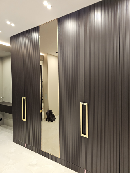 Общий вид фасадов корпусной мебели с рифлёной текстурой, центральной зеркальной панелью и симметричным расположением дверей, создающих эффект монолитной стены хранения в современном интерьере