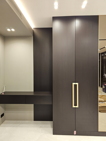 Встроенная корпусная мебель с распашными фасадами из рифлёного МДФ в тёмном оттенке, интегрированная в интерьер с подвесной консолью, скрытым креплением и минималистичными латунными ручками, выполненная во всю стену с точной подгонкой по архитектуре помещения