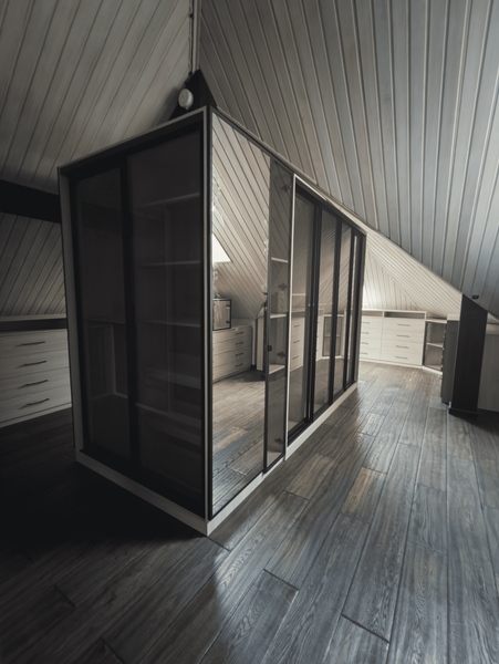 Мансардная гардеробная с островным модулем и стеклянными фасадами