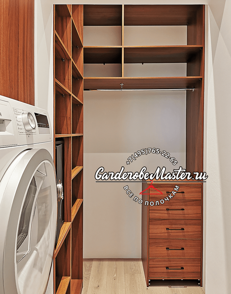 Гардеробная комната с корпусной системой хранения из натурального шпона, включающая вертикальные открытые полки, секции для длинной и короткой одежды на металлических штангах и мобильный блок ящиков, интегрированная в узкое помещение с бытовой техникой