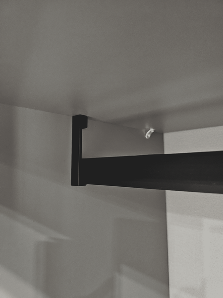 Штанга для одежды с чёрным металлическим держателем в гардеробной системе