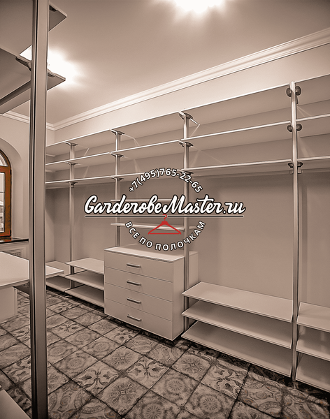 Открытая гардеробная система GarderobeMaster с металлическим каркасом, длинными штангами для одежды, модульными полками и центральным комодом, выполненная в светлой гамме с напольной плиткой с орнаментом