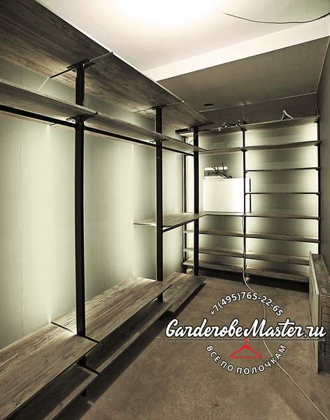 Открытая гардеробная система с чёрными металлическими стойками и полками под дерево, выполненная в индустриальном стиле, с линейной компоновкой, открытым хранением одежды и акцентом на брутальные материалы и строгую геометрию пространства