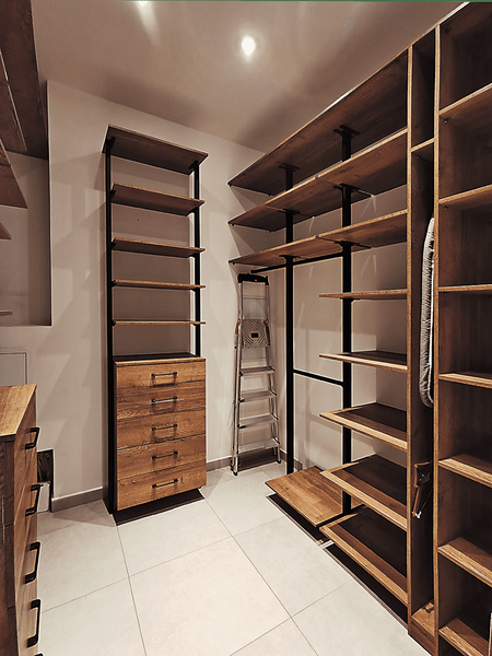 Открытая гардеробная система в стиле лофт с массивными деревянными полками и вертикальными металлическими стойками, выдвижными комодами и продуманной эргономикой хранения в отдельной комнате.