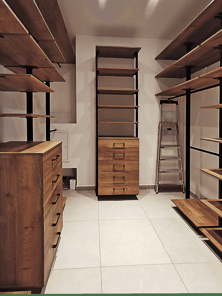 Просторная гардеробная комната с открытыми деревянными стеллажами, вертикальными металлическими опорами, центральным комодом и продуманной организацией хранения по периметру помещения