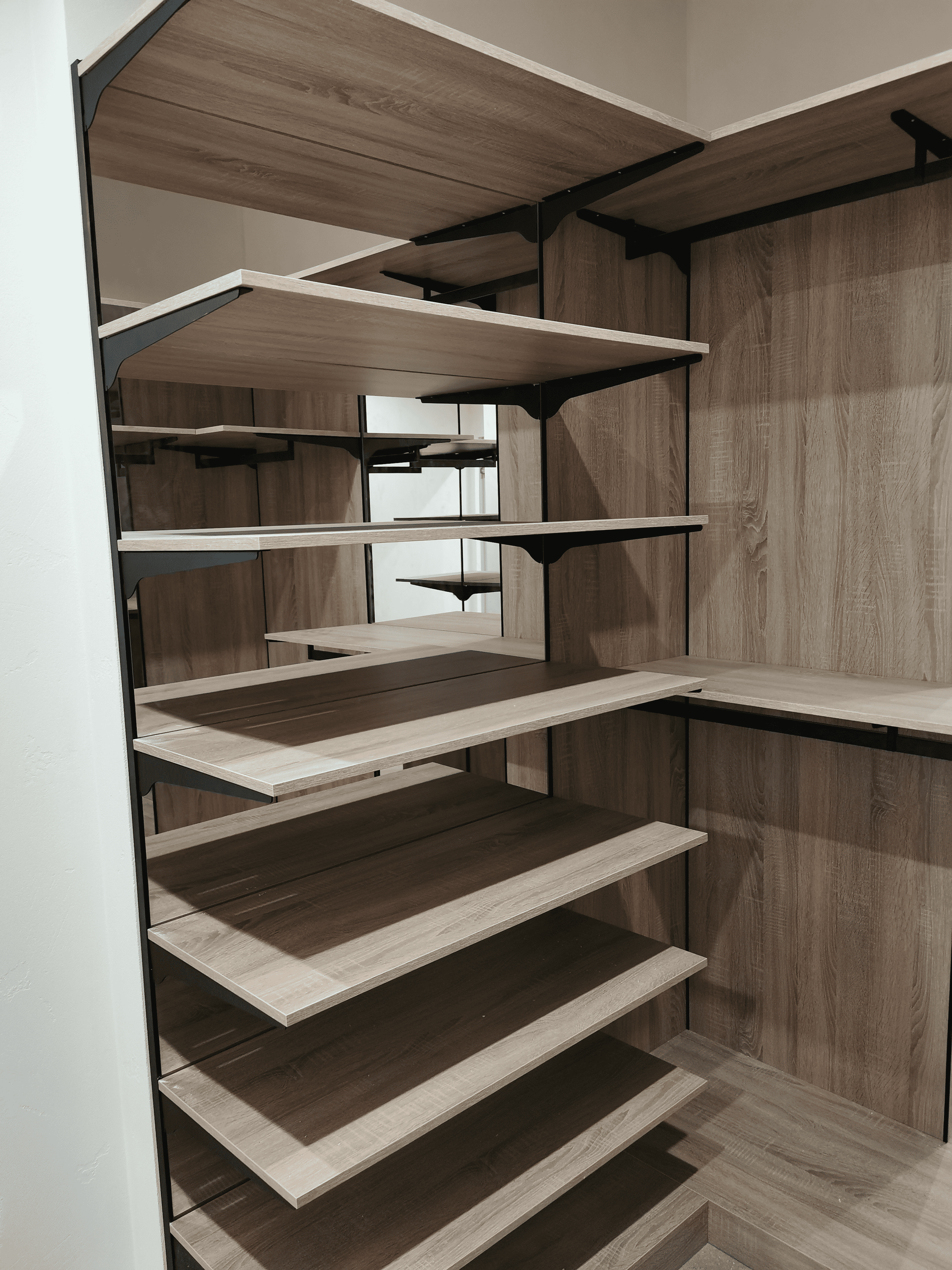 Открытая секция гардеробной с многоуровневыми деревянными полками на металлических кронштейнах