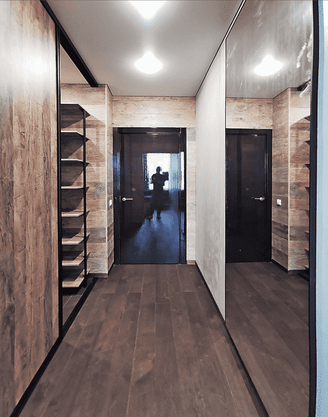 Проходная гардеробная с раздвижными зеркальными дверями, встроенными полками по бокам и отделкой стен под натуральное дерево