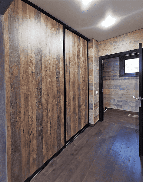 Раздвижные двери в гардеробную с фасадами под дерево и чёрным алюминиевым профилем, интегрированные в интерьер коридора