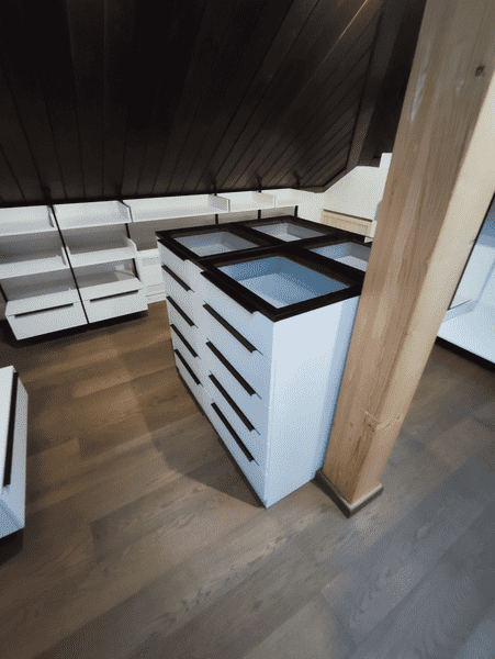 Гардеробная система под мансардной крышей с напольными модулями, подвесными комодами и штангами для одежды