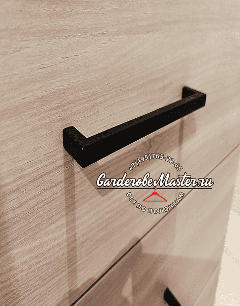 Деталь мебельной фурнитуры — чёрная металлическая ручка на фасаде выдвижного ящика из текстурированного ЛДСП, акцент на качестве материалов и аккуратной сборке