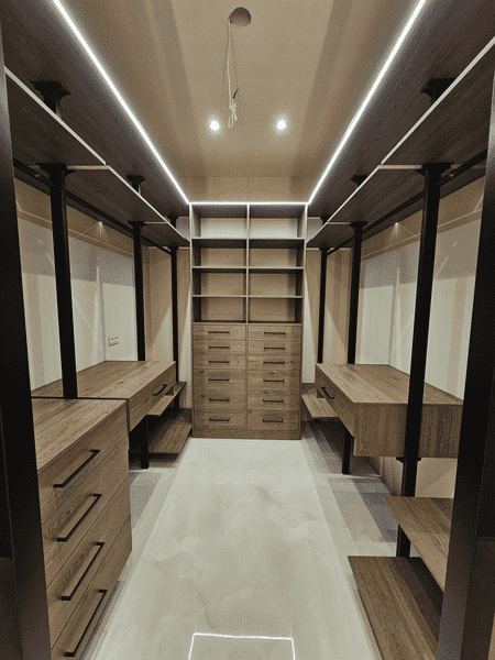 Фрагмент гардеробной комнаты с выдвижными ящиками и рабочей поверхностью, металлический каркас, тёплый оттенок древесной текстуры, функциональное зонирование пространства