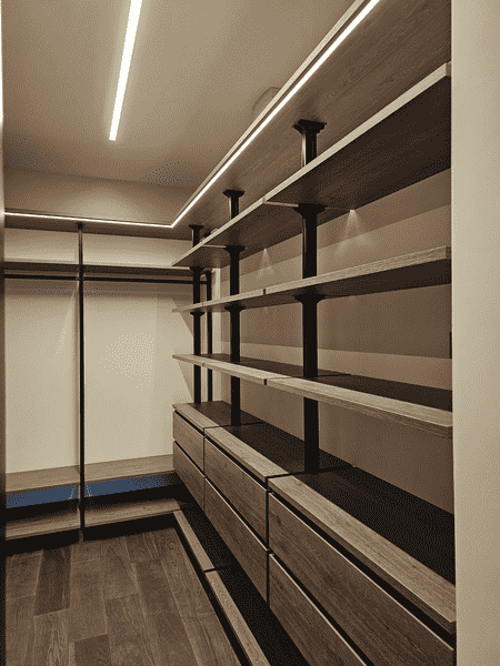 Гардеробная система с потолочной подсветкой и встроенными полками по периметру.