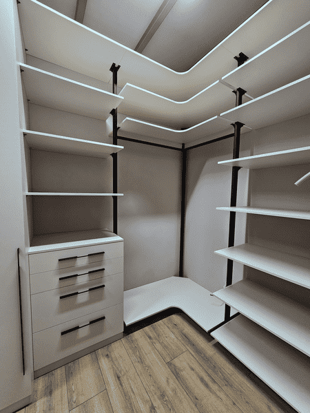 Гардеробная система с интегрированной подсветкой и угловой компоновкой. Дизайн гардеробной комнаты с акцентом на удобство и порядок.