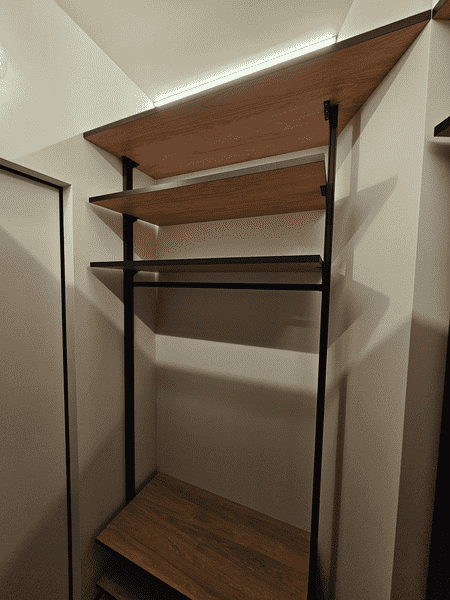 Металлическая гардеробная система с деревянными полками и встроенной подсветкой. Современный дизайн гардеробной комнаты с продуманной организацией хранения.